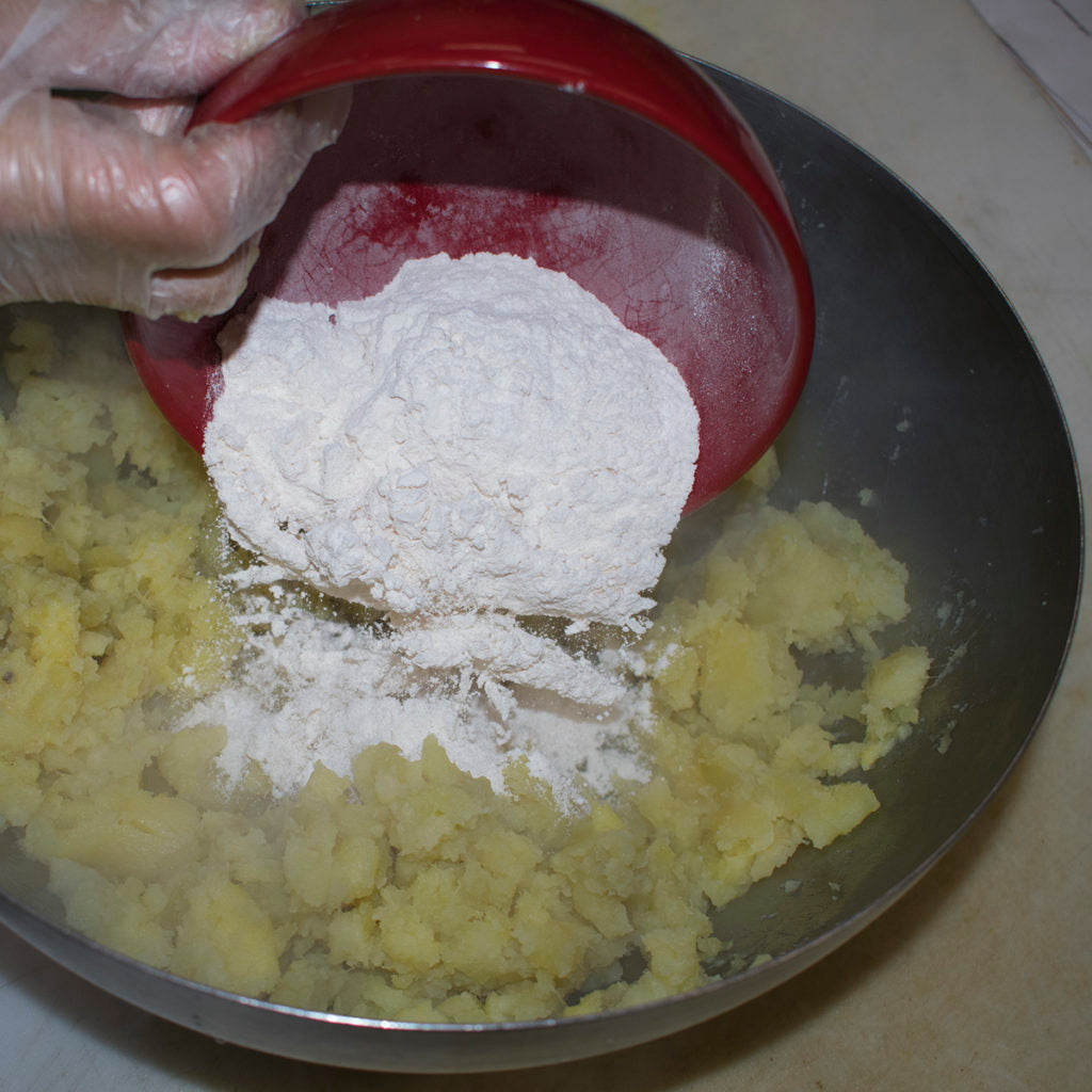 Add flour gradually to the mashed potatoes