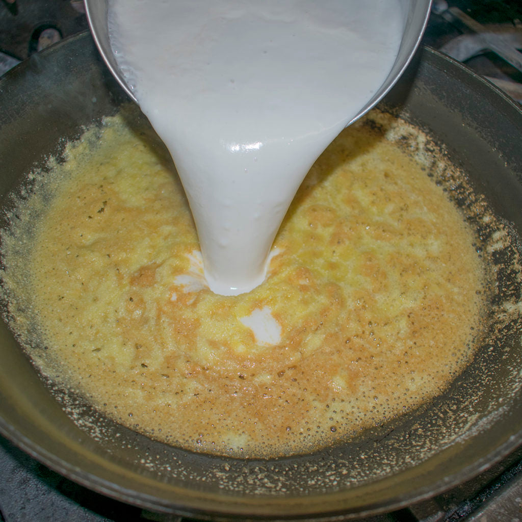 Slowly pour the steamy milk into the roux, stirring constantly