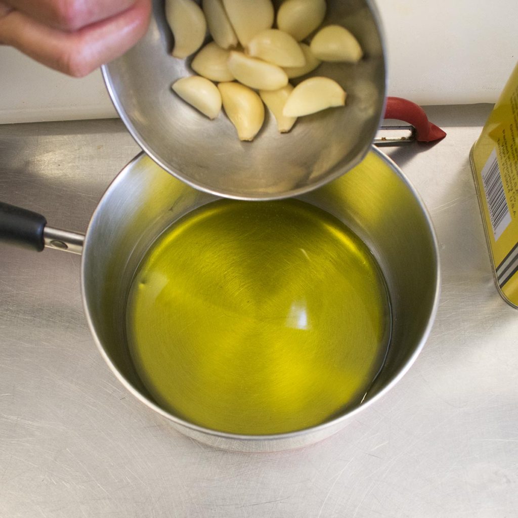 Put the olive oil in a small saucepan, add the garlic cloves and simmer on low for 8-10 minutes, or until soft and lightly browned.