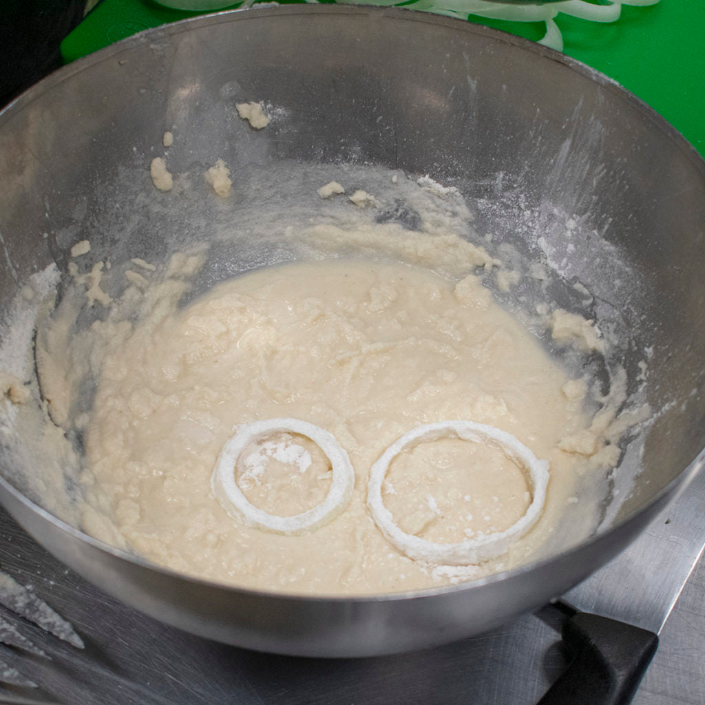 Dust the onion rings in the dusting flour, then dip them one at a time into the batter