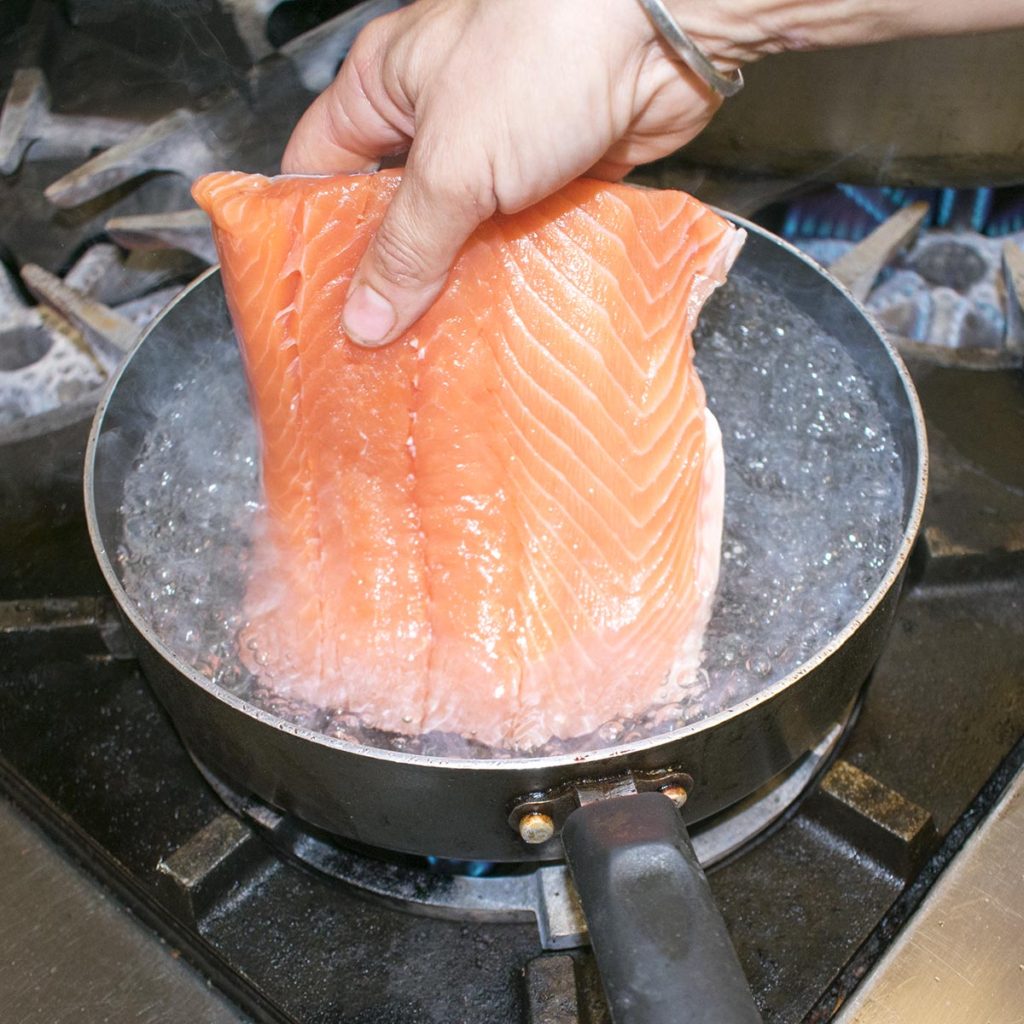 Gently lower the skinless aip salmon filet into 2 inches of simmering water.