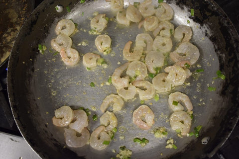 Add olive oil, half the garlic, half the ginger and half the scallions and shrimp to the wok