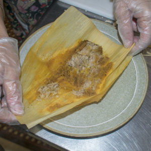 Open the husk on a tamale and spoon sauce over it.